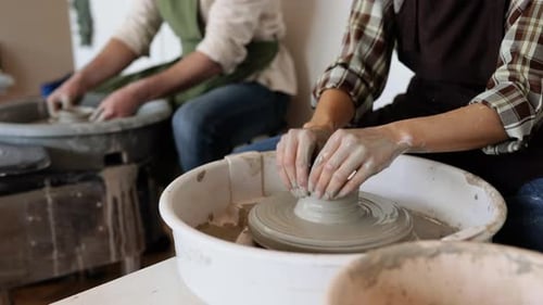 People Shaping Clay on Pottery Wheel