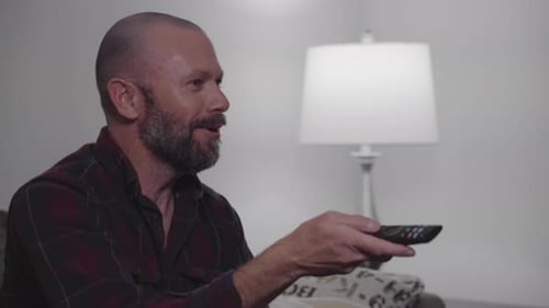 Man with Remote Sitting on Couch Inside