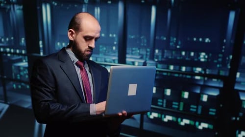 Man Working with Laptop in Dark Server Room