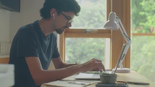 Young Adult Working on Laptop at Home Office