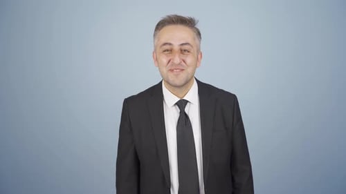 Man in Suit Smiles and Waves Hello