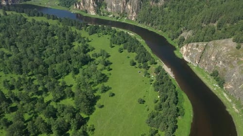 Revealing Shot of a River Flowing Among Green Forest and Mountains