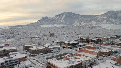 Low drone shot moving forward of Boulder Colorado, rocky Flatiron mountains, and Pearl Street after