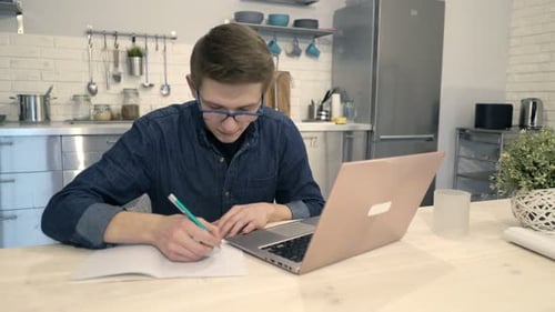 Teenage Boy Studying with Laptop in Kitchen