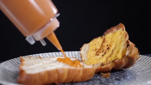 Serving Breakfast with Croissant Sandwich Green Salad and Tomato Being Poured with Cheese Sauce Slow