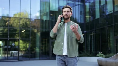 Man Talking on Phone Outside Modern Office Building