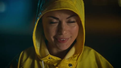 Smiling woman wearing yellow raincoat in the rain
