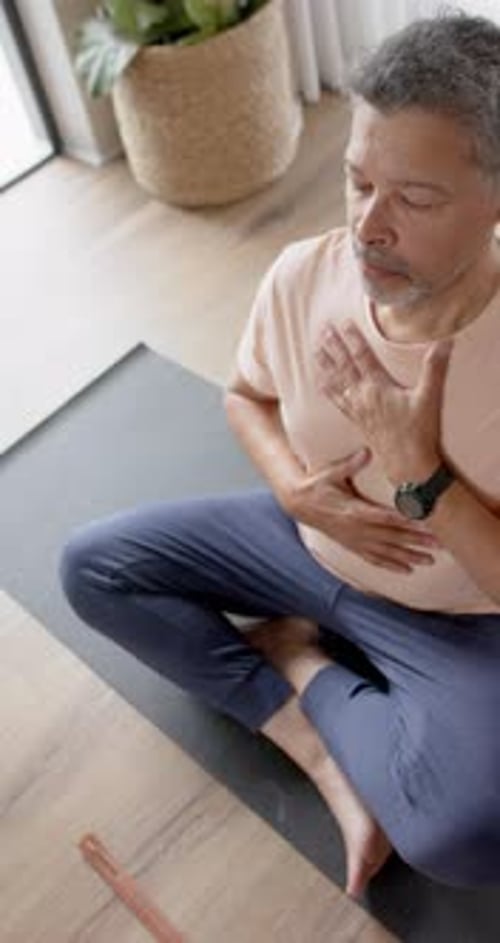 Man Meditates at Home on Yoga Mat