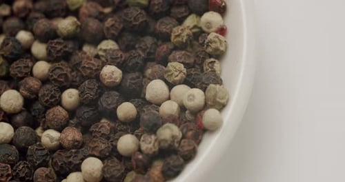 Black and White Peppercorns in a White Bowl