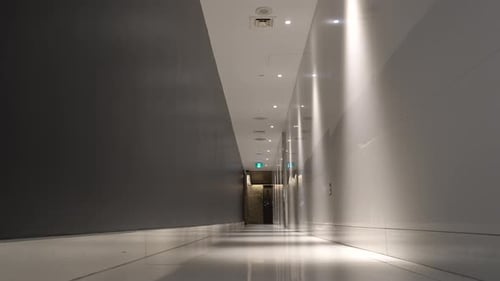 Men Walking Down Modern Lit Hallway