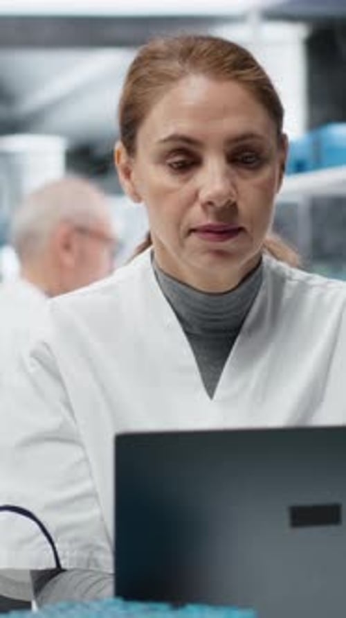 Woman in Lab Coat Works on Computer
