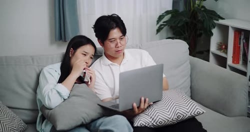 Couple Relaxing on Sofa with Laptop