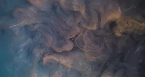 Abstract blue and gold paint swirls in liquid