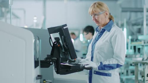 In einer Hightech-Fabrik verwendet die Ingenieurin einen Greenscreen-Computer zur Programmierung von Pick and Place Elect