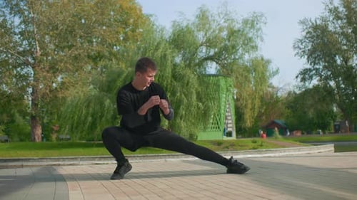 Young Man Stretching in a Park Before Exercise