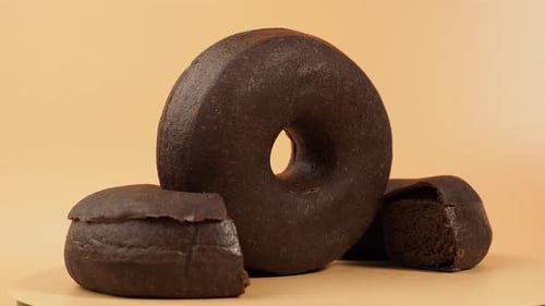 Rotating dark vegetarian donut on an orange background.