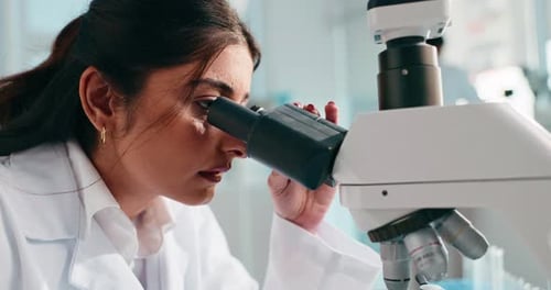 Woman Researcher Looking Through a Microscope in Lab