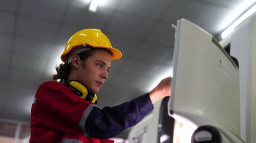 Young industrial worker operating cnc machine at metal machining industry. Industry Worker Entering
