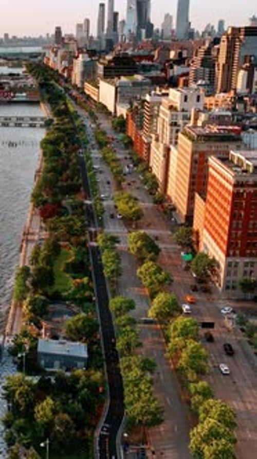 Flight above the waterfront of Hudson River. Beautiful green park and highway separating water