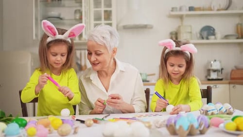 Grandmother and Granddaughters Decorating Easter Eggs at Home