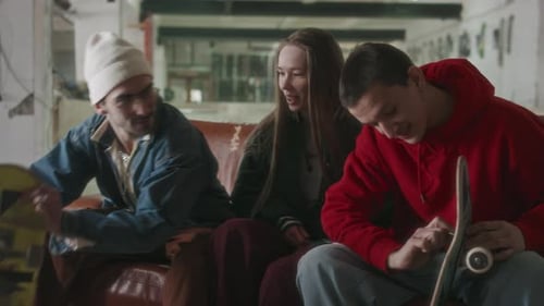 Friends Talk Skateboarding on Couch Indoors