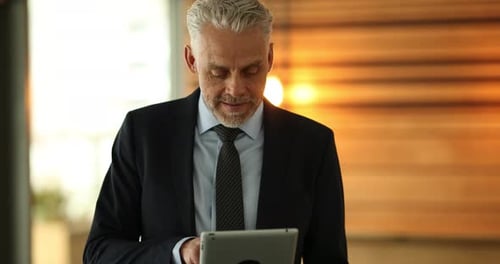 Smiling Mature Businessman Standing in the Hallway of a Modern Office Working
