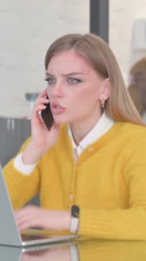 Woman Typing on Laptop Gets Upsetting Phone Call