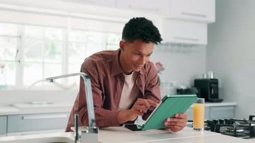 Young Adult Using Tablet in Bright Modern Kitchen