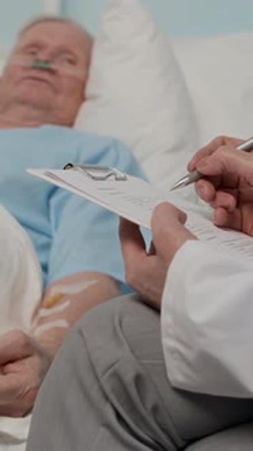 Healthcare Worker Filling Card of Aged Patient in Hospital Ward