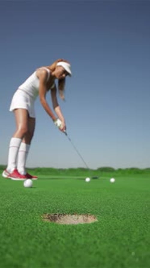 Mujer pelirroja golpea hábilmente tres pelotas de golf en el green