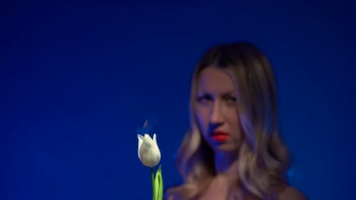 Dolly-Aufnahme einer unscharfen jungen schönen blonden Frau mit üppigen roten Lippen, die eine brennende Peitsche hält