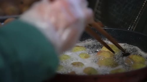 Falafel Being Fried in Oil with Chopsticks