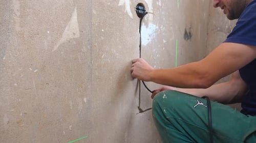 Electrician Kneeling To Set Up Electrical Outlet Connections