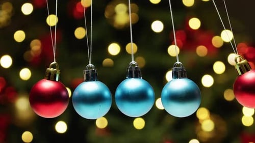 Swinging Christmas Ornaments in front of Bokeh Lights