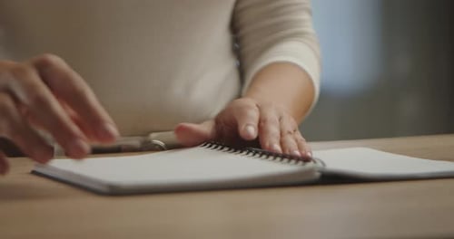 Hands Tearing Pages From a Spiral Notebook