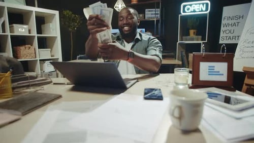 Successful African Businessman Holding Cash In Dark Office. African American Man Counting Money I...