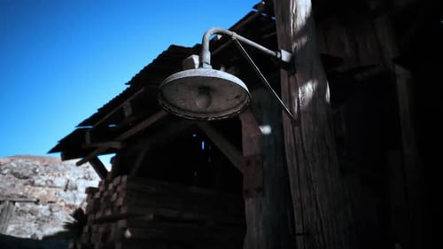 Vintage Hanging Light Fixture in an Old Wooden Building Under a Clear Sky
