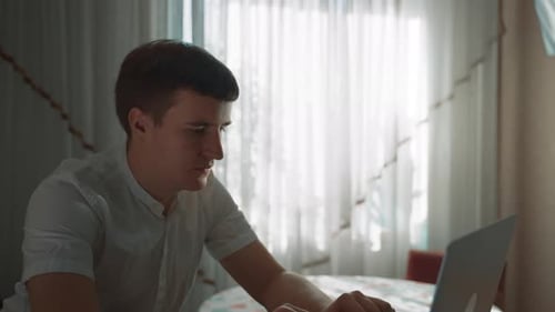 Young Adult Using Laptop at Table Indoors