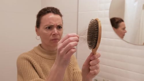 A woman removes her hair from a comb.