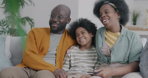 Smiling Family Watching Television Together on Couch
