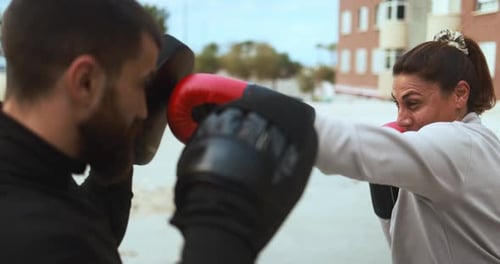 Woman Boxing with Trainer in Urban Environment