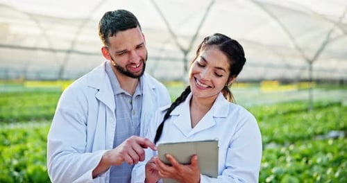 Scientists Reviewing Data on Tablet in Greenhouse