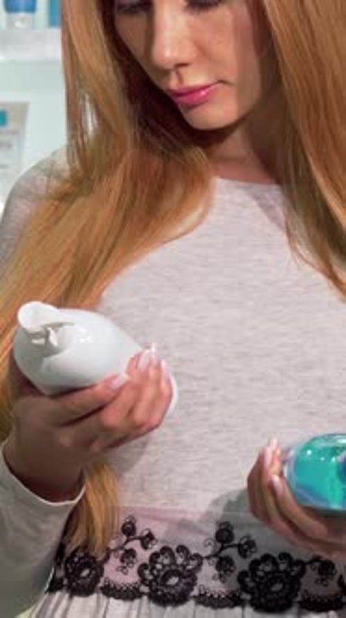 Thoughtful Woman Comparing Shampoo Bottles in a Vibrant Pharmacy Aisle