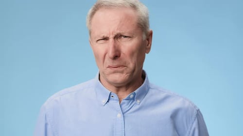 Ein Mann zeigt in einem in Auflösung aufgenommenen Video seinen Ausdruck von Ekel vor blauem Hintergrund
