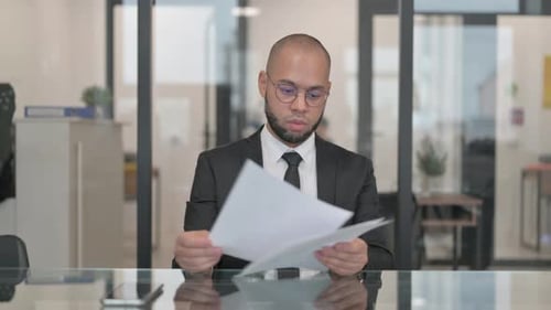 Suited Man Reviews Documents at Office Desk
