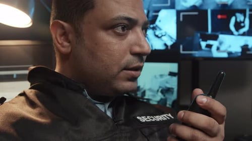 Security Guard Speaking into Walkie Talkie in Control Room