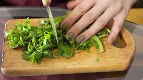 Closeup View of Female Hands Cutting Parsley By Metal Knife on Wooden Table