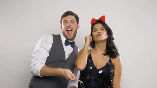 Cheerful young couple posing with party props and having fun indoors
