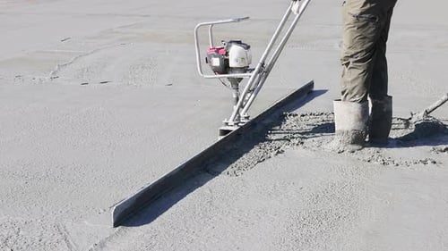 Workers Pour Smooth Concrete Slab at Construction Site During Works Hours in Effort to Create Solid