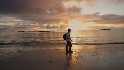 Silhouettenansicht eines Mannes mit Rucksack, der Zeit auf einem Spaziergang entlang der Küste bei sonnigem Wetter verbringt